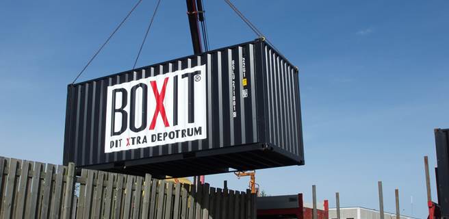 Levering af container over hegn Container løftes over hegn